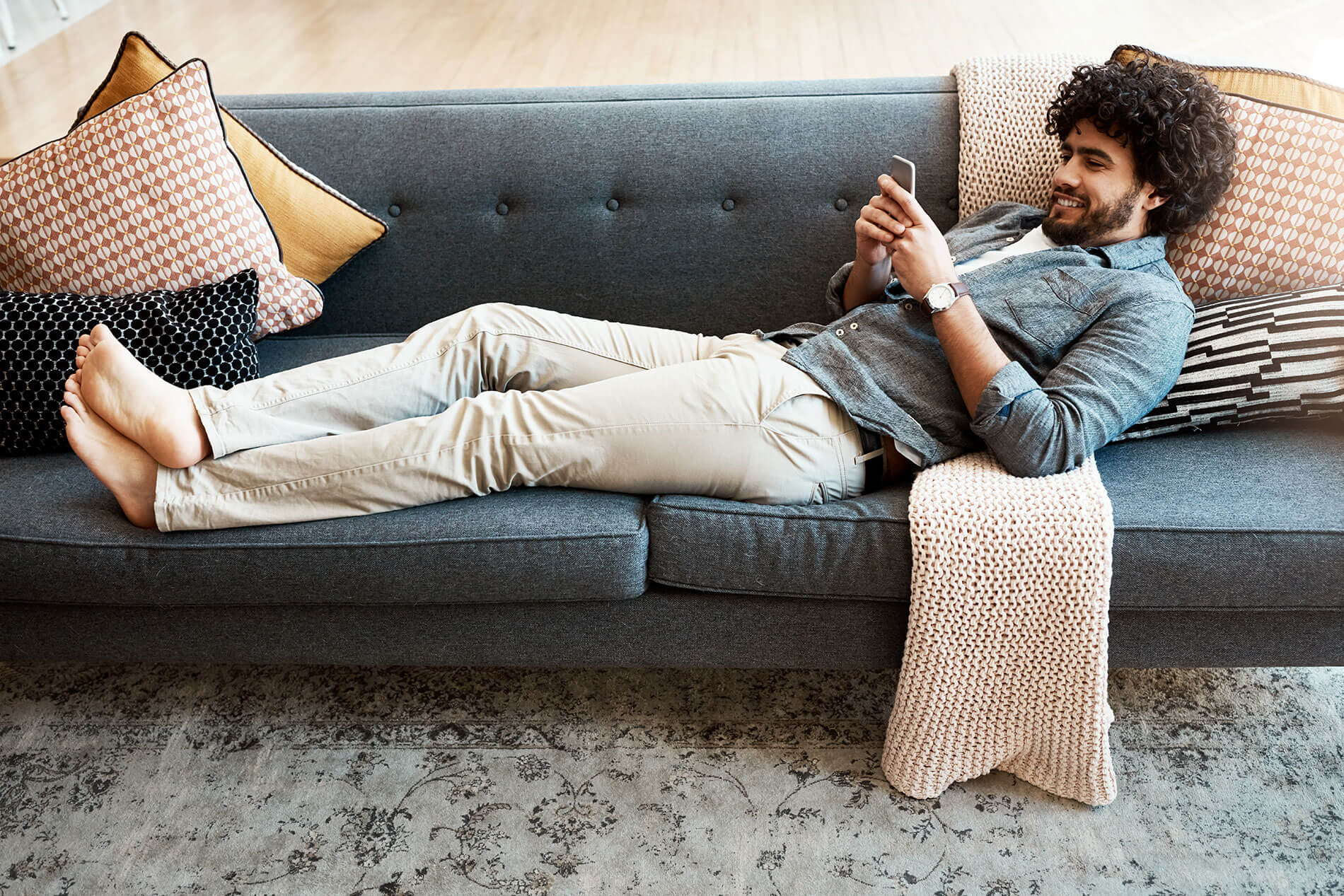 Man lounging on the couch on his phone