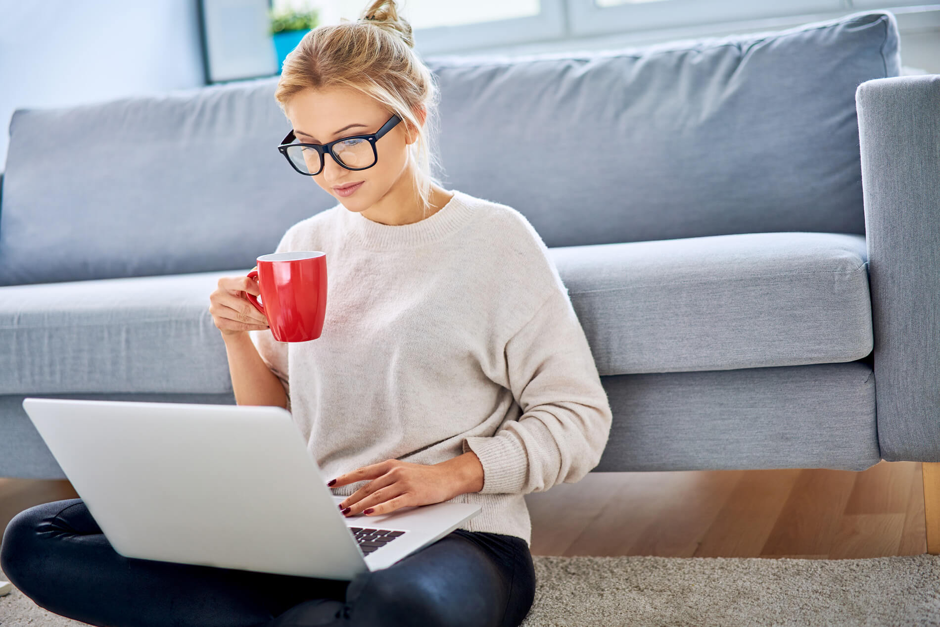Woman drinking coffee looking at laptop