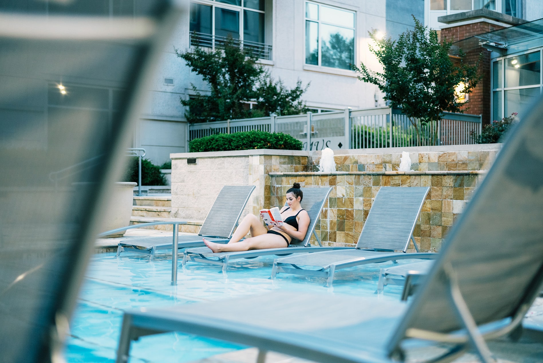 Domus Apartments woman sitting by pool