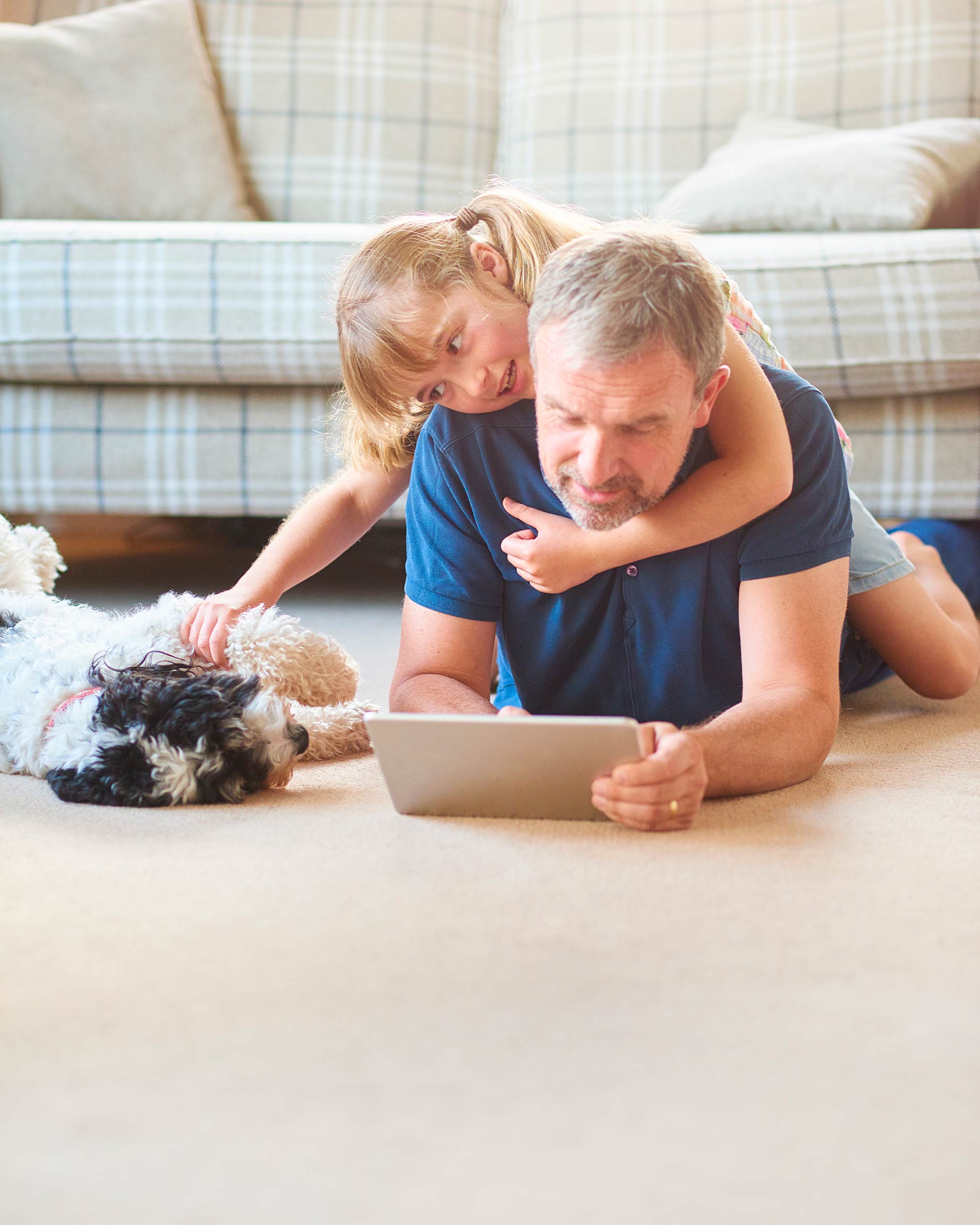 father and daughter play on tablet with dog