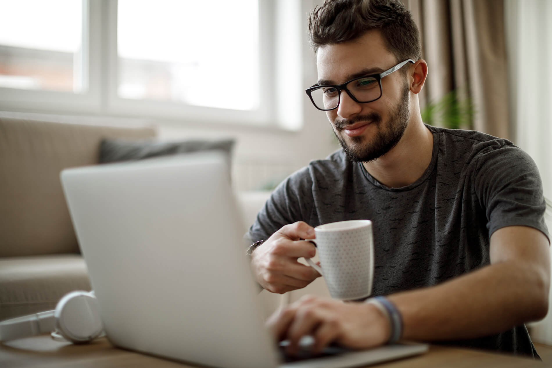 Man sipping coffee and working at laptop