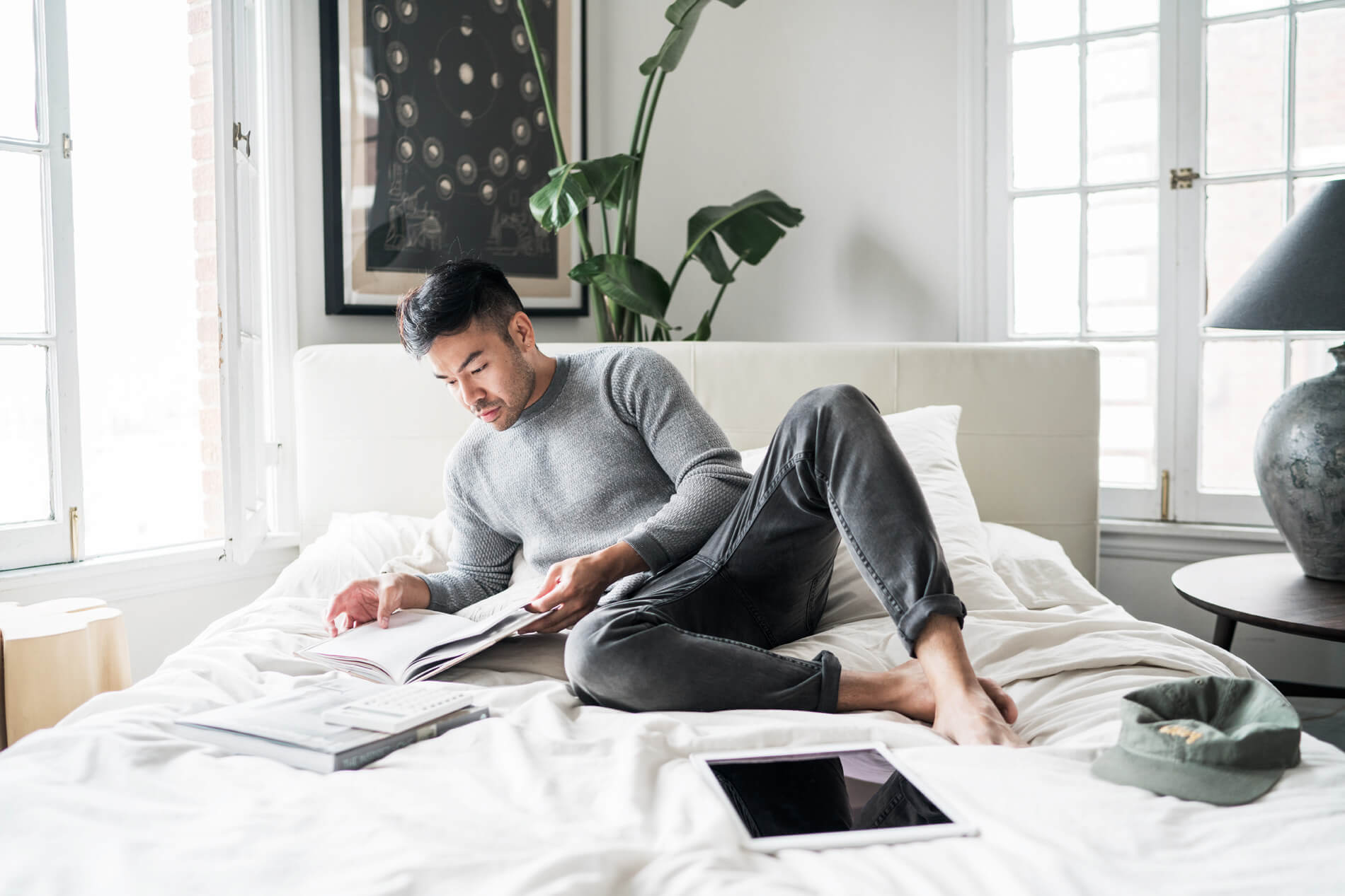Man sitting on his bed looking at a notebook