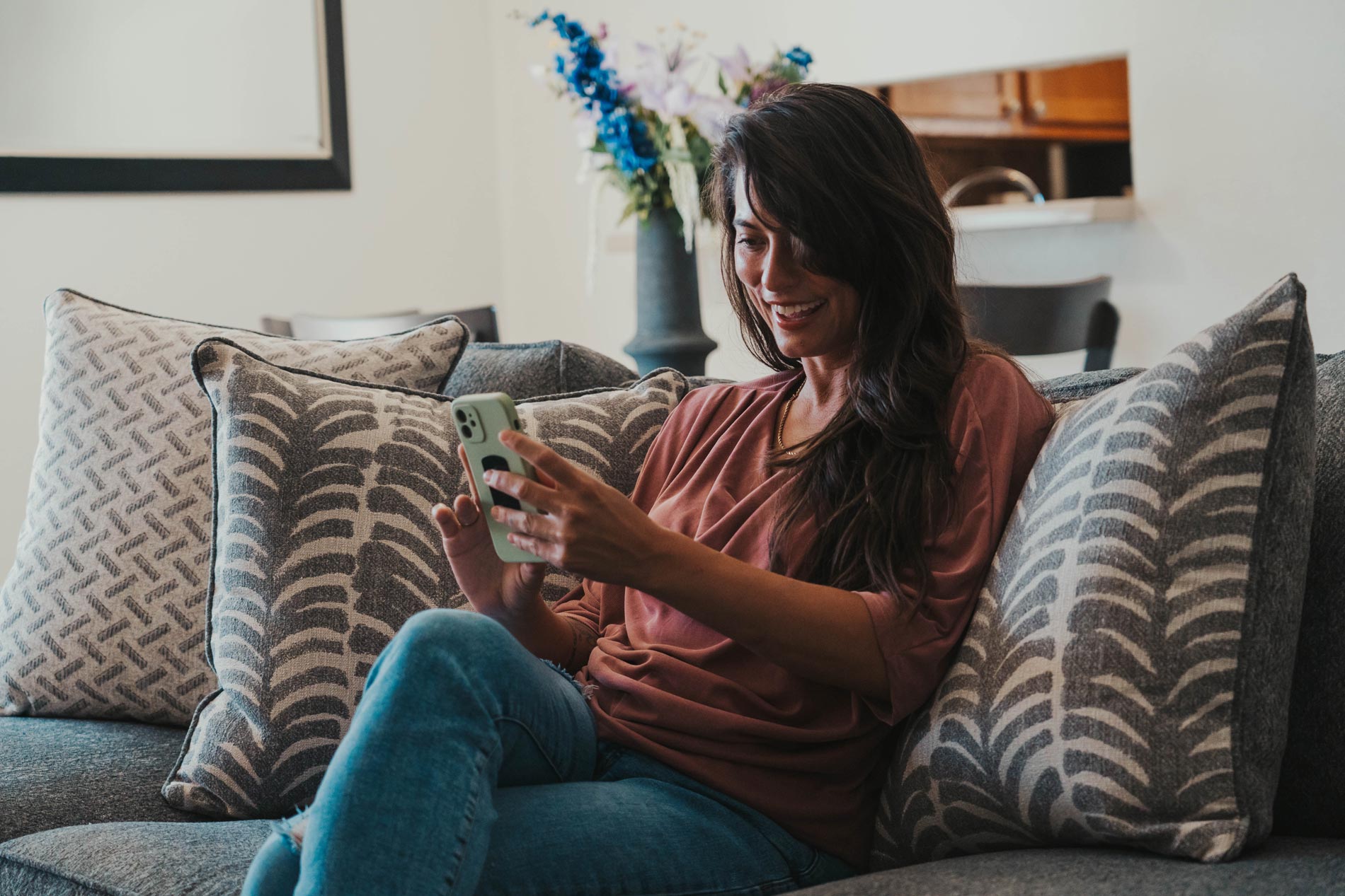 Woman sits on couch with phone