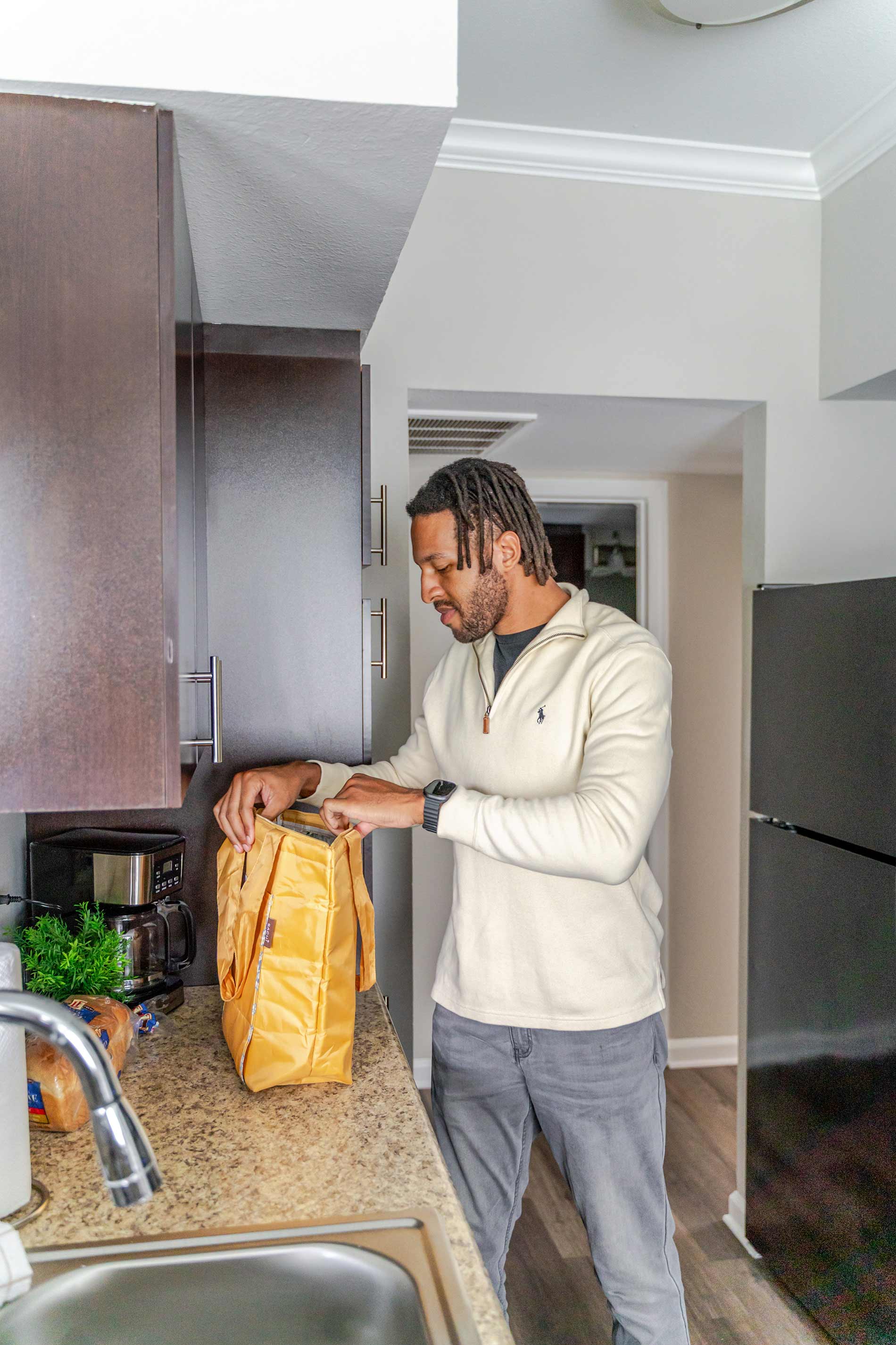 Colonnade man unloads groceries in kitchen