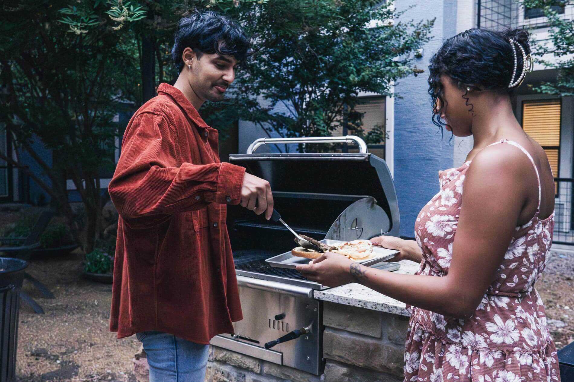 Cool Springs a man serves a woman a burger from a grill