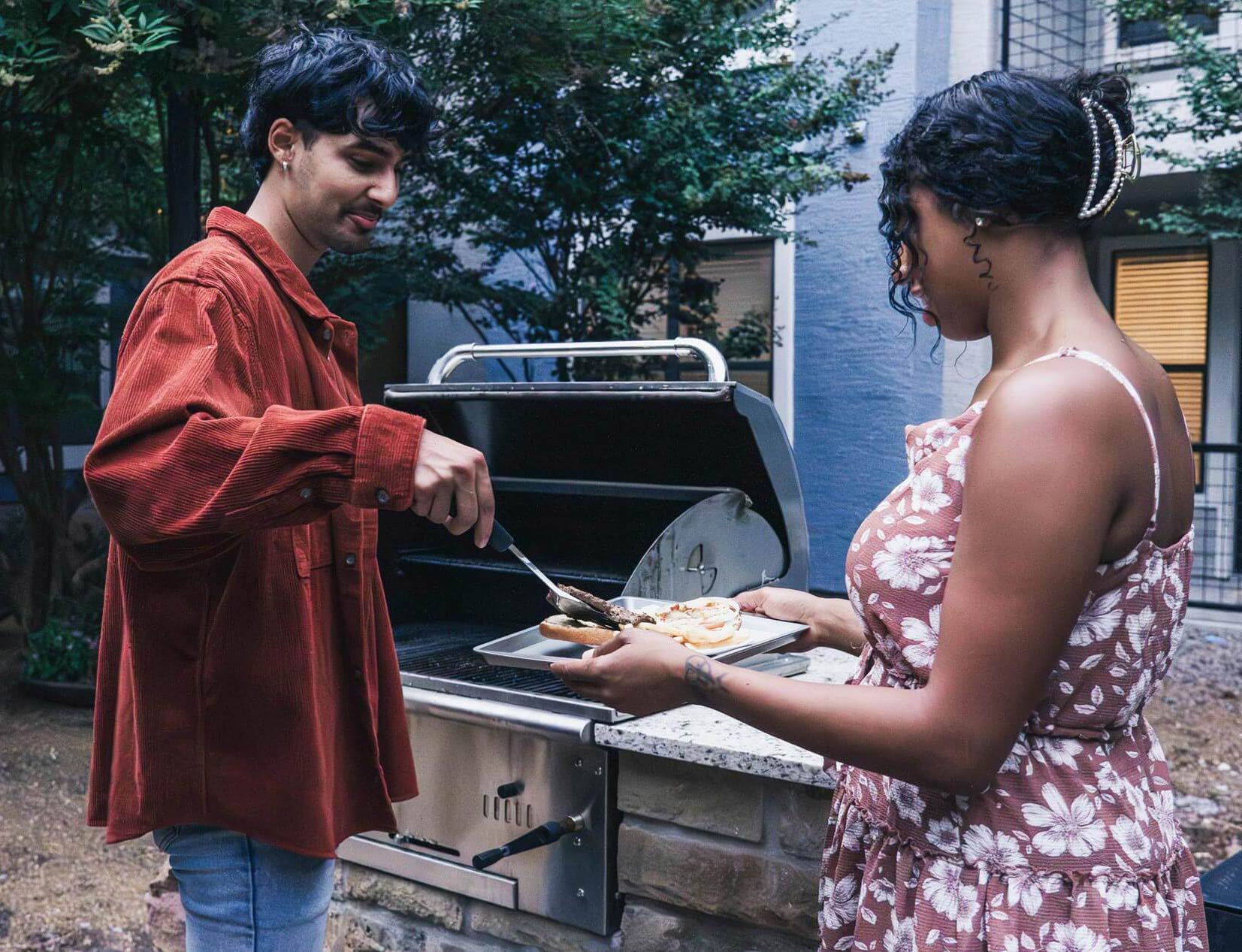 Cool Springs a man serves a woman a burger from a grill