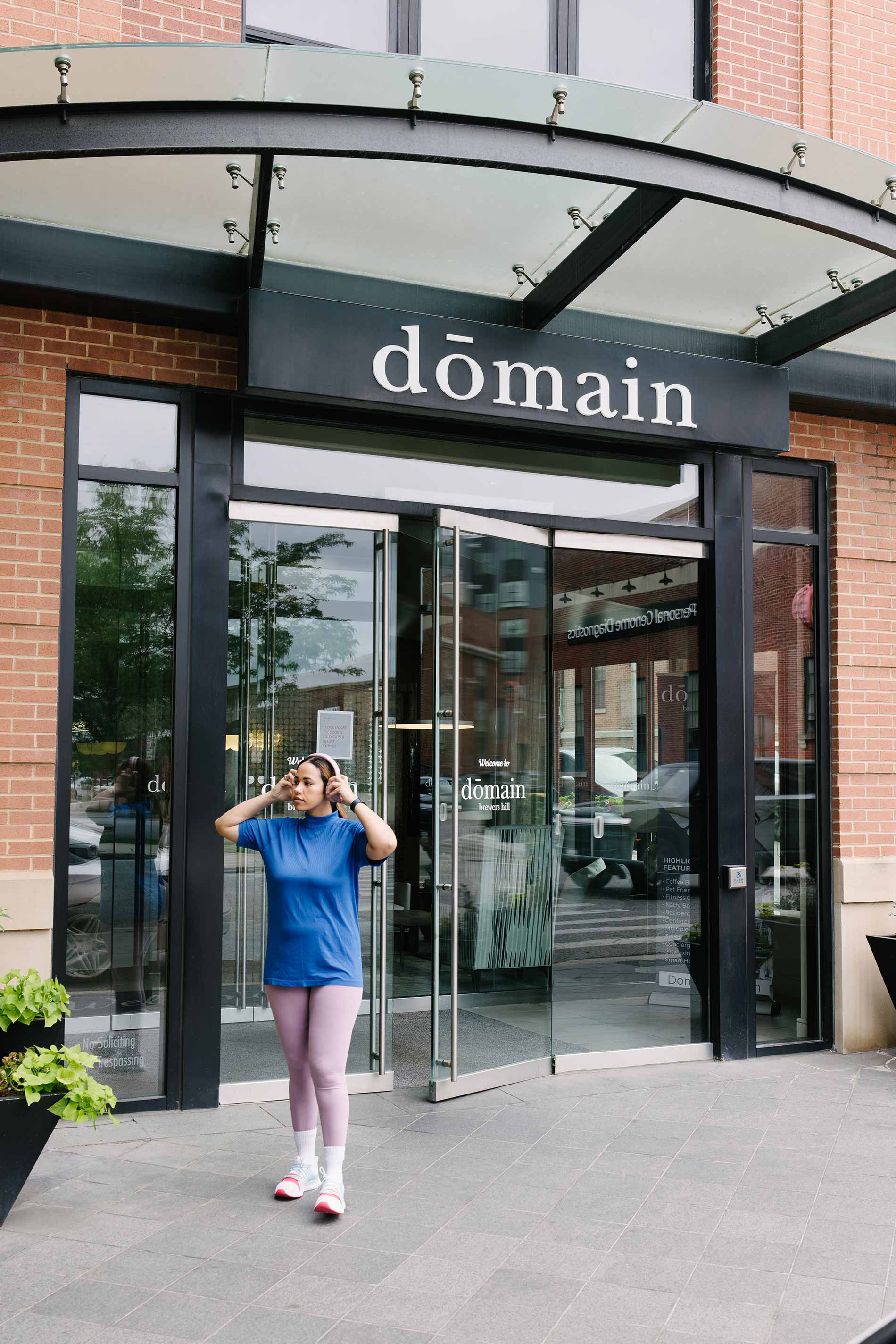 Domain Brewers Hill woman exits building with headphones