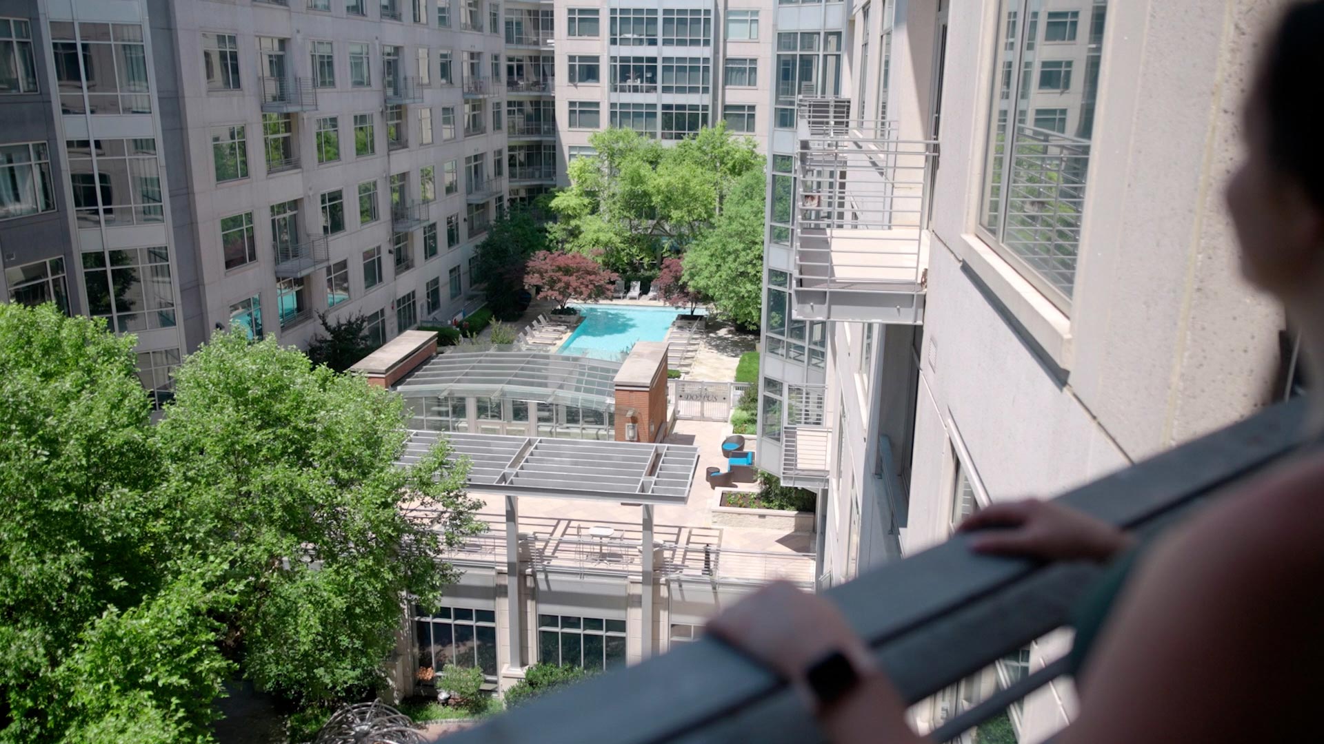 Domus woman looks over balcony to courtyard pool