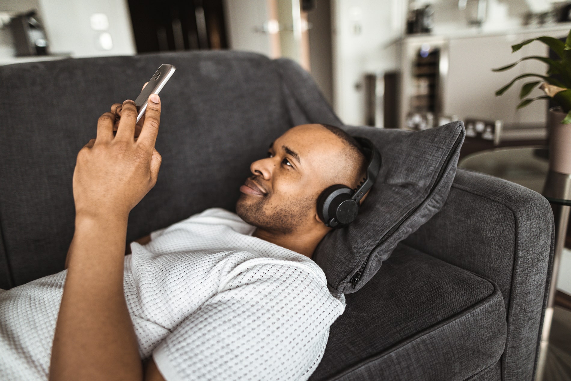 African American man on couch scrolling on phone