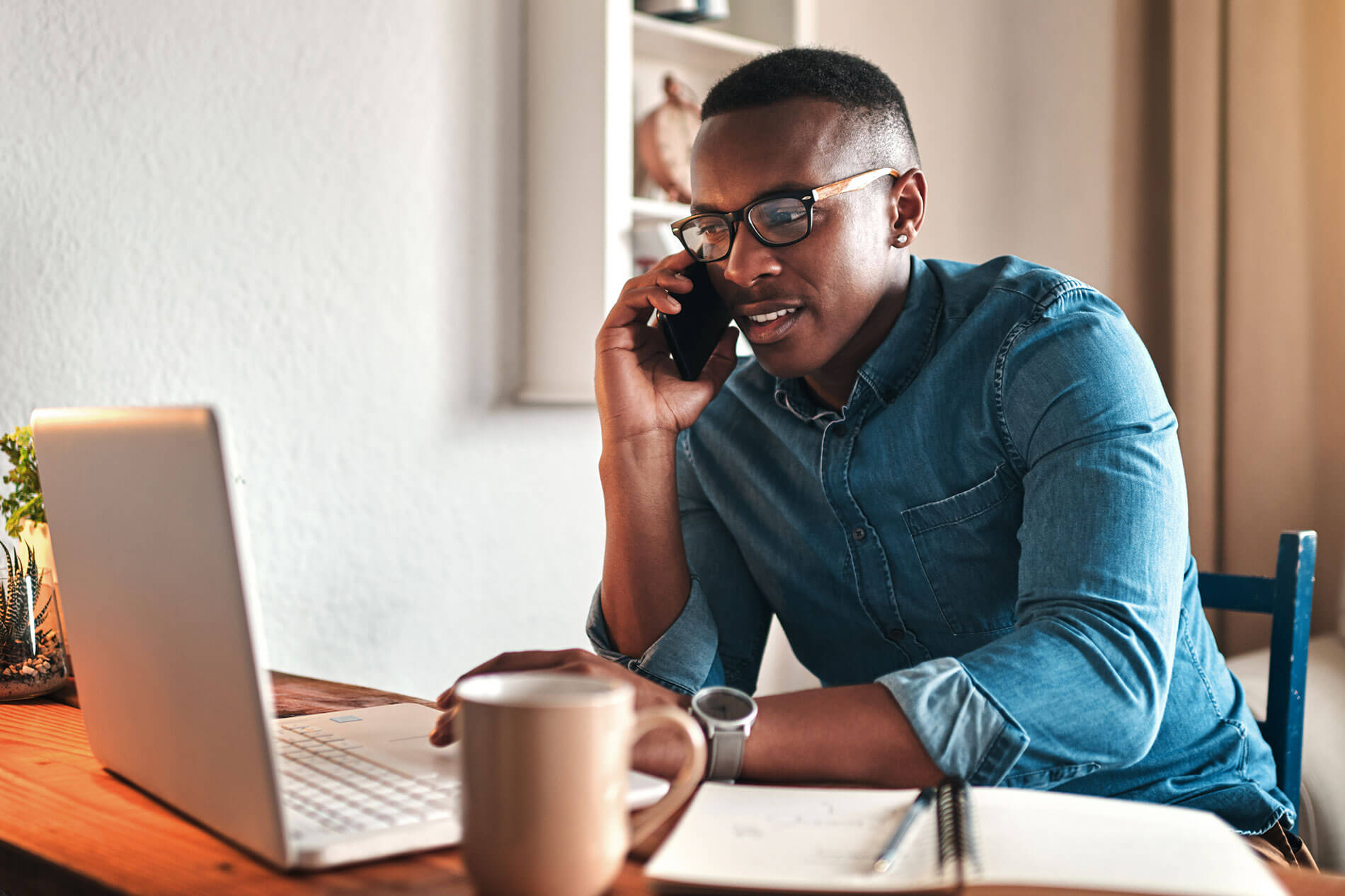 Young man on the phone looking at laptop