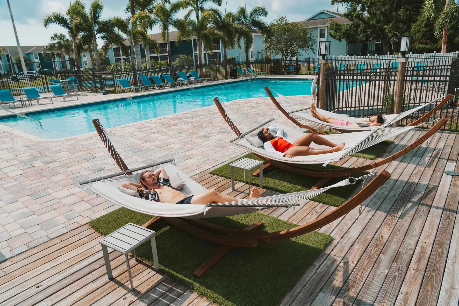 Inlet Bay three people sit in hammocks by pool