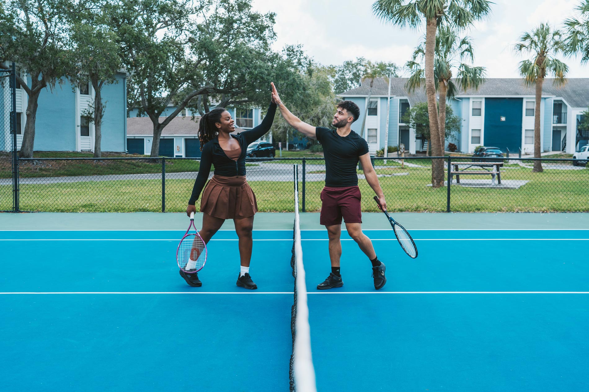 Inlet Bay two people high five at the tennis court