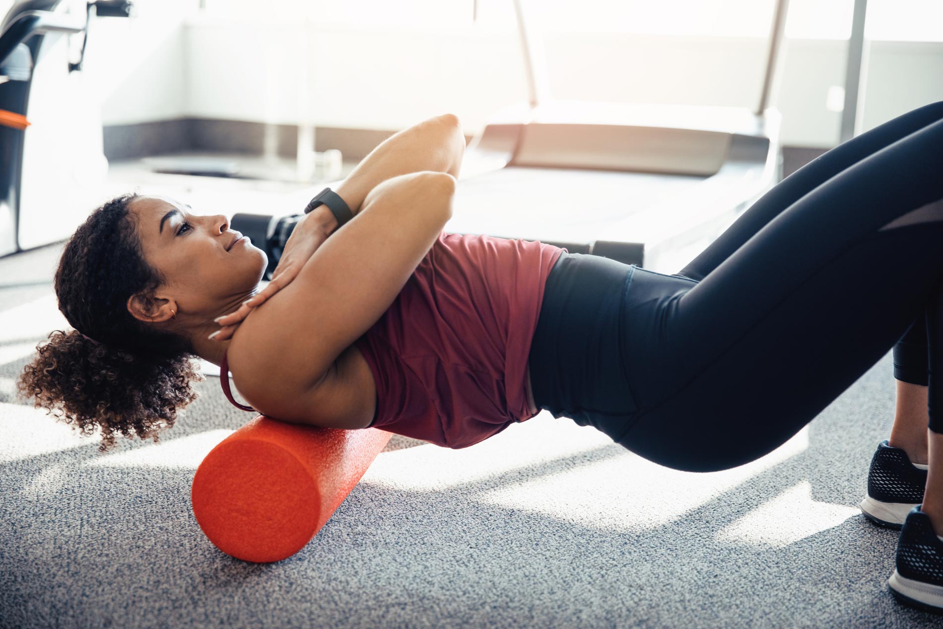 woman uses a back roller in a fitness center