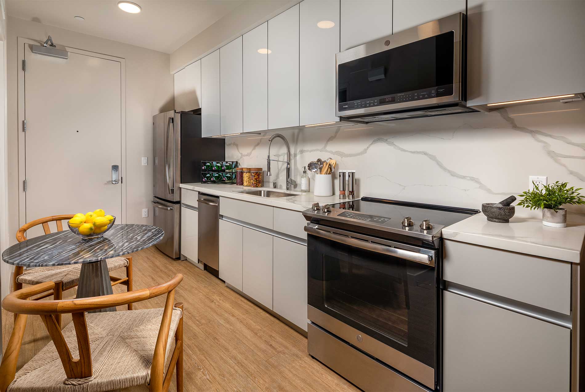 Modern apartment kitchen with white cabinetry and stainless steel appliances