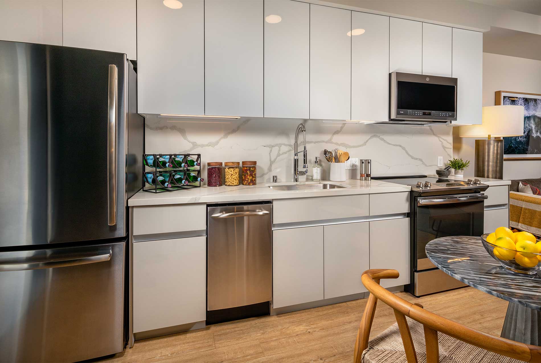 White apartment kitchen with quartz island and stainless steel appliances