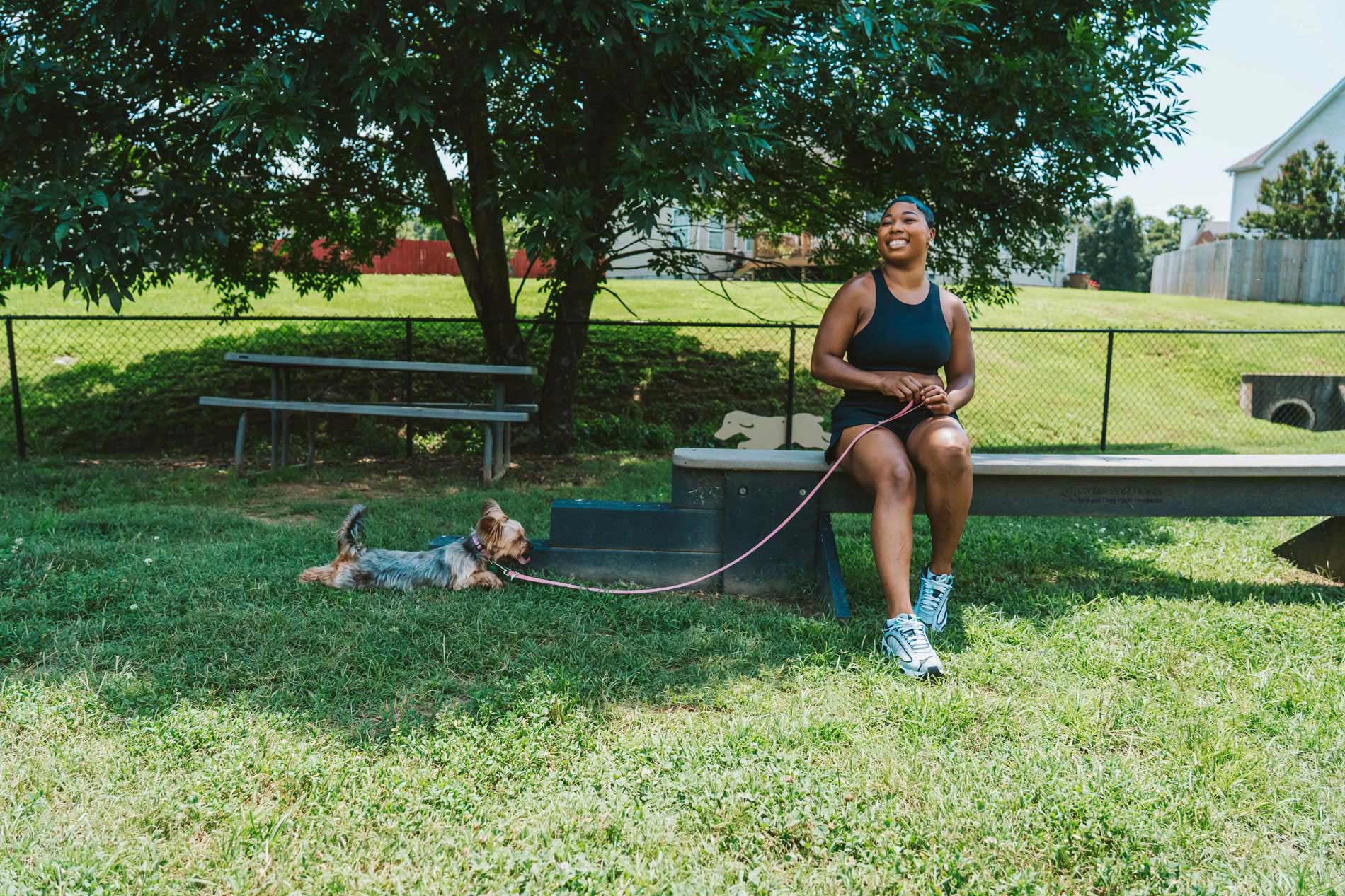 Polo Park woman sits in dog park with small dog Polo Park woman sits in dog park with small dog