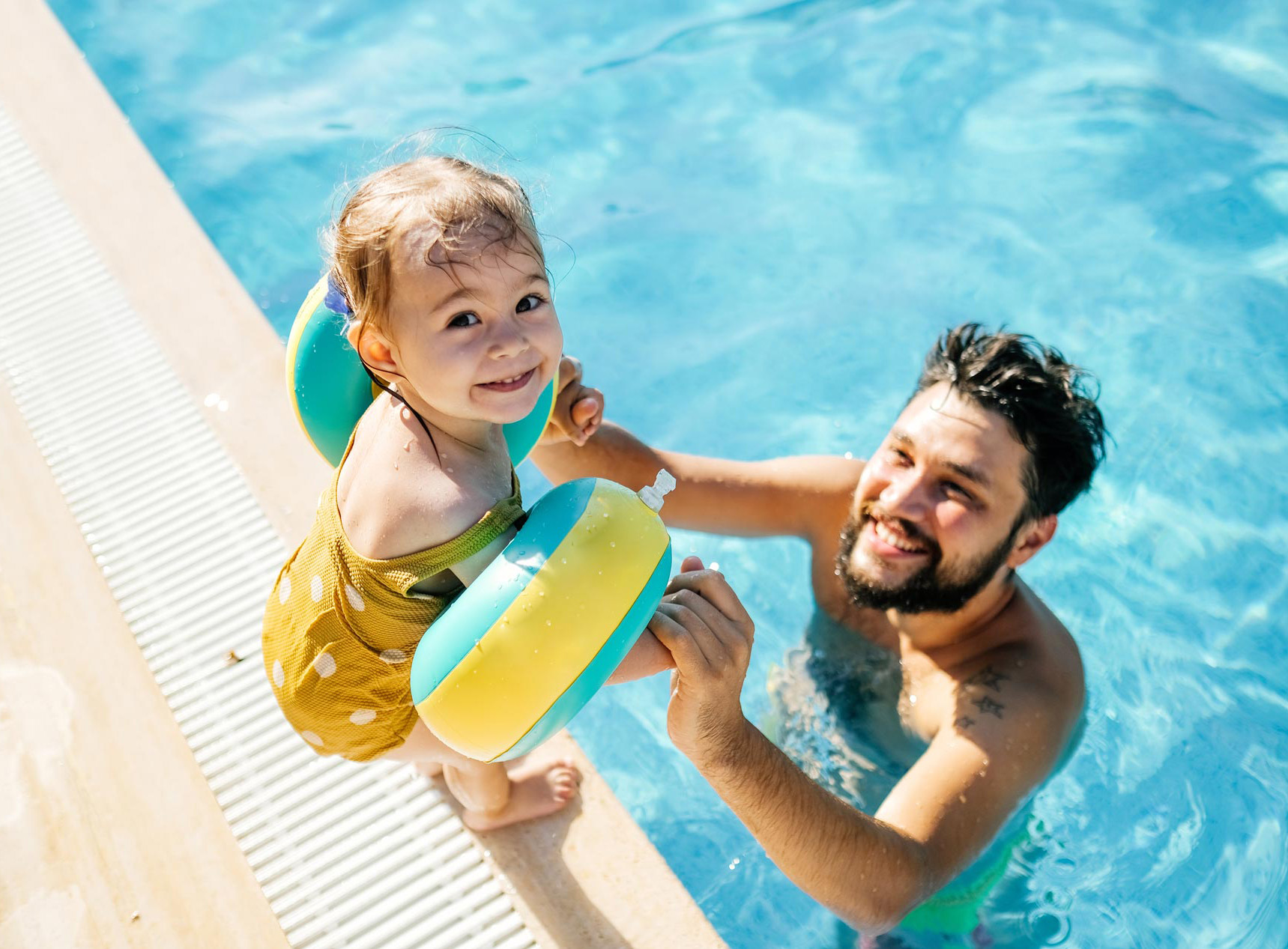 father and baby play in the pool