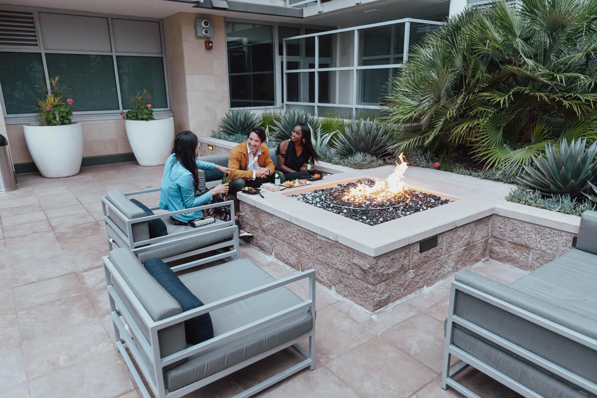 Strata three people sit by the fire pit