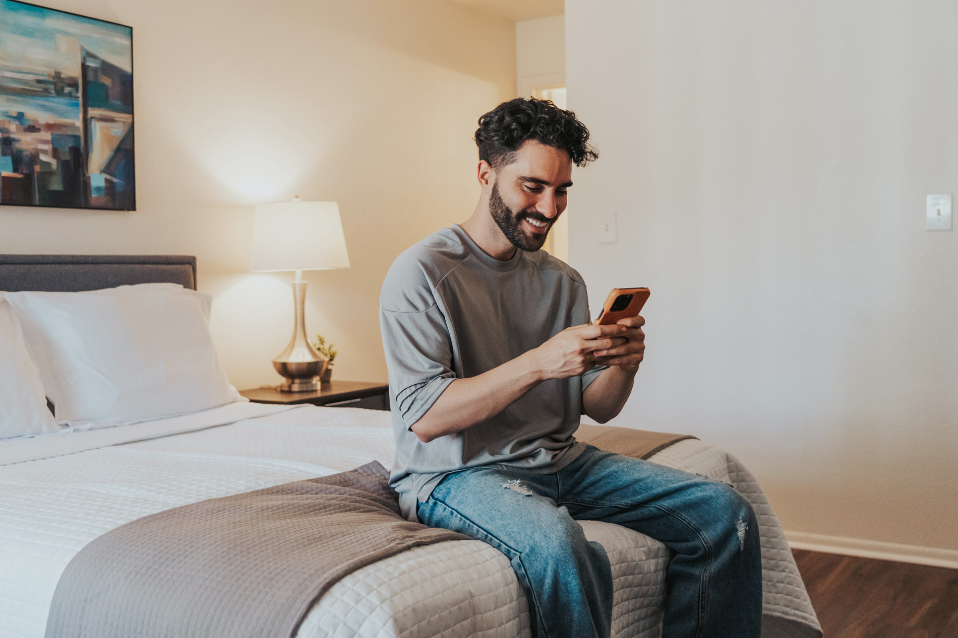 Summit West man plays on phone in bedroom