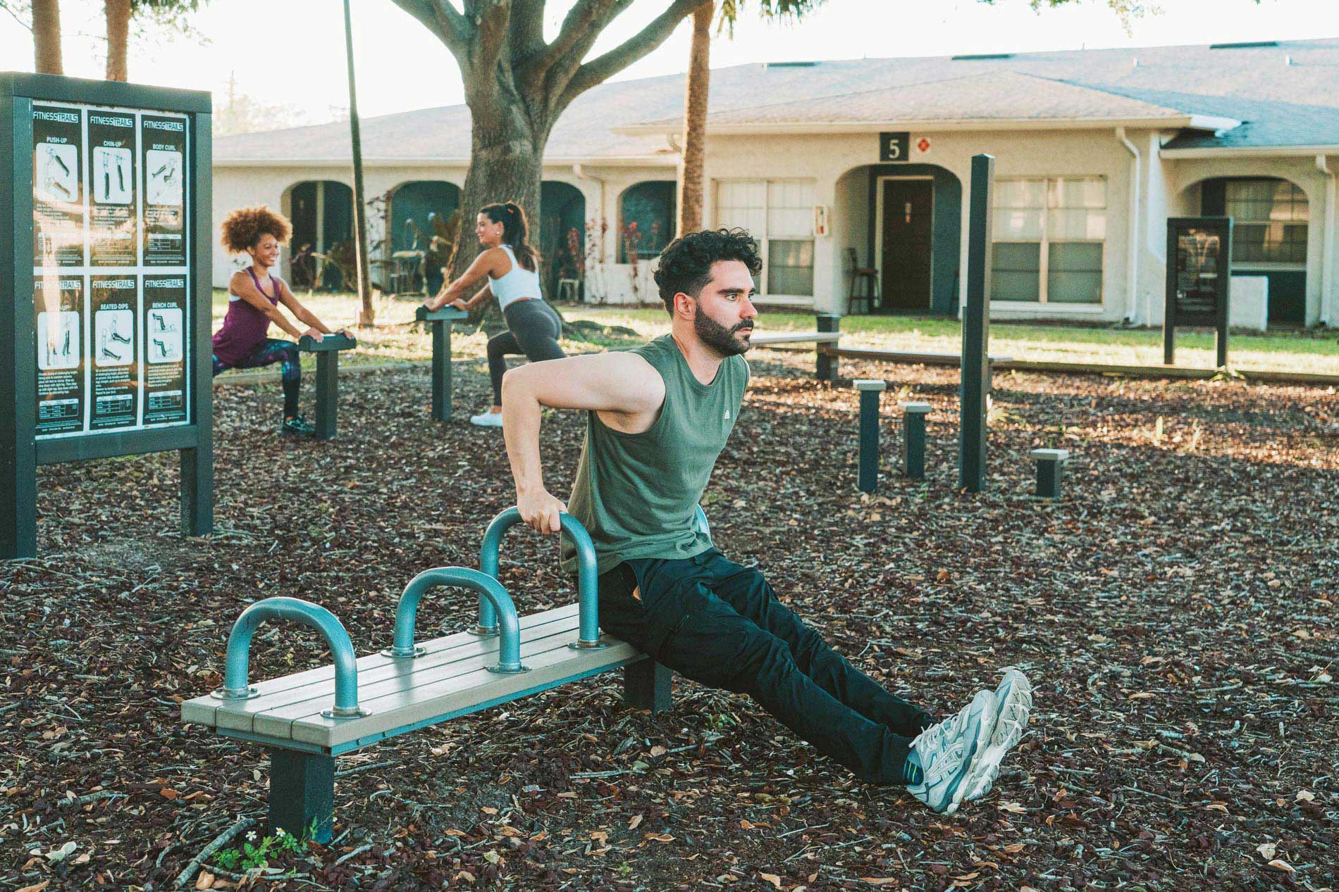 Summit West three people exercise at the outdoor fitness area