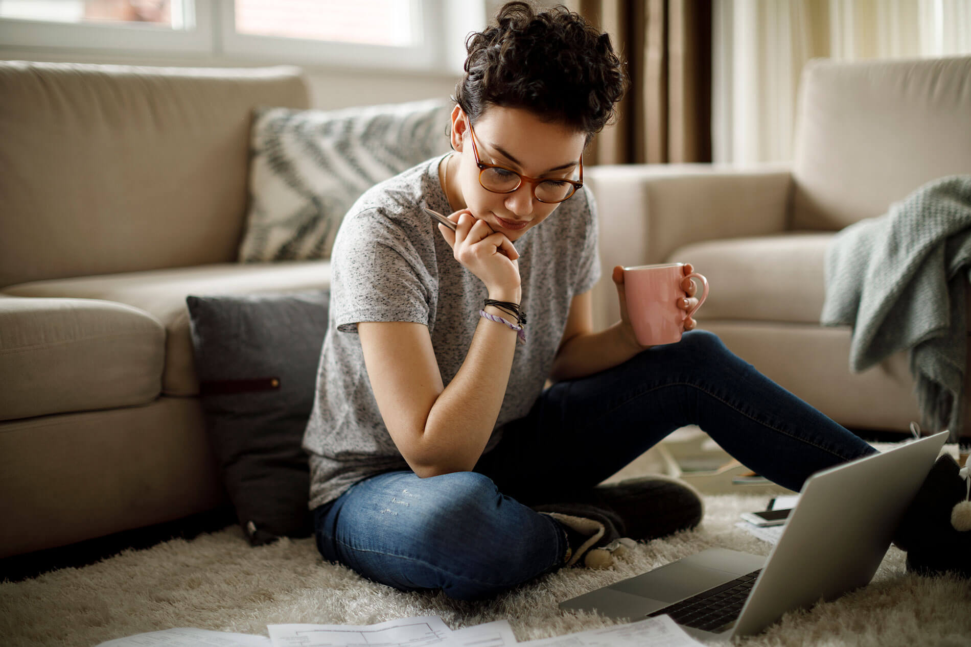 Young woman sitting on floor and working on laptop