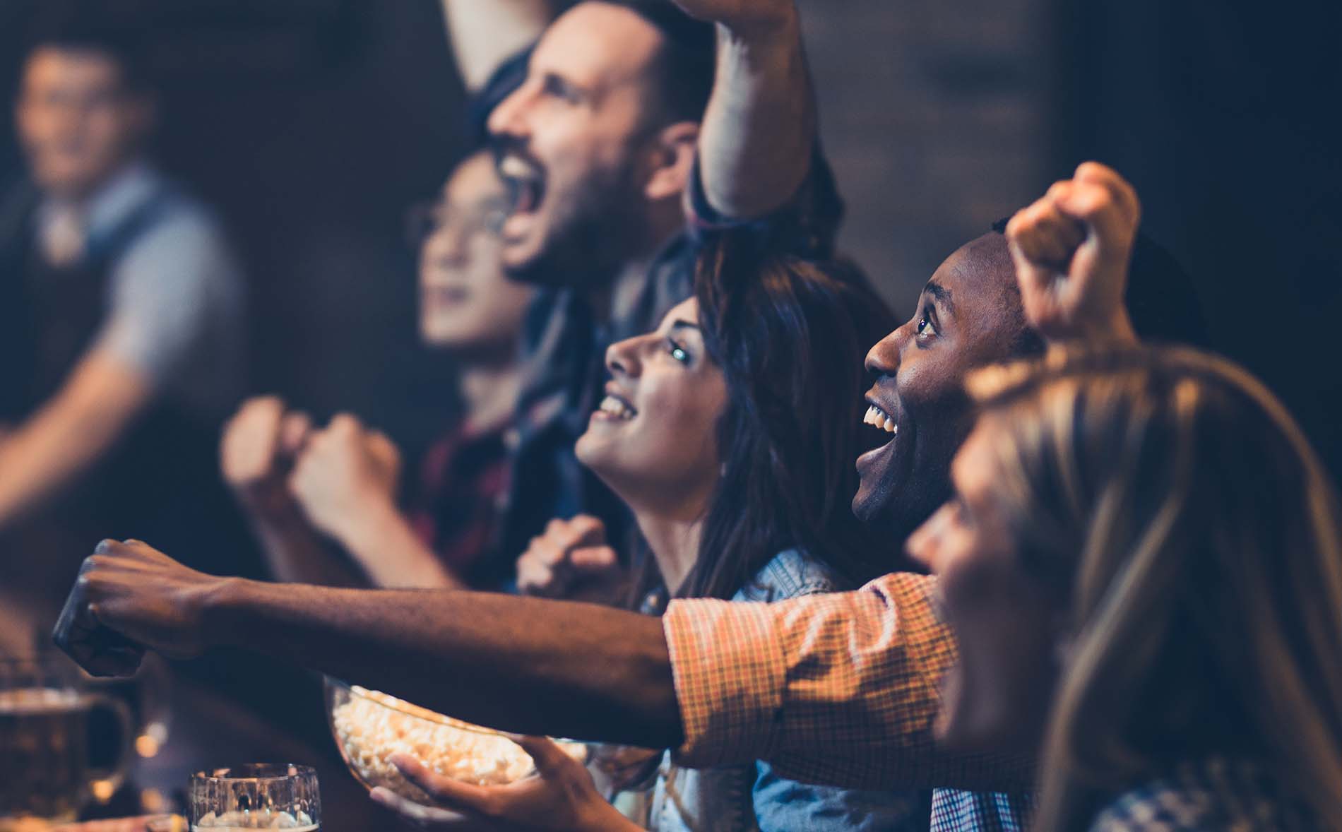 Group of cheerful soccer fans celebrating the winning of their team while watching a game in resident lounge