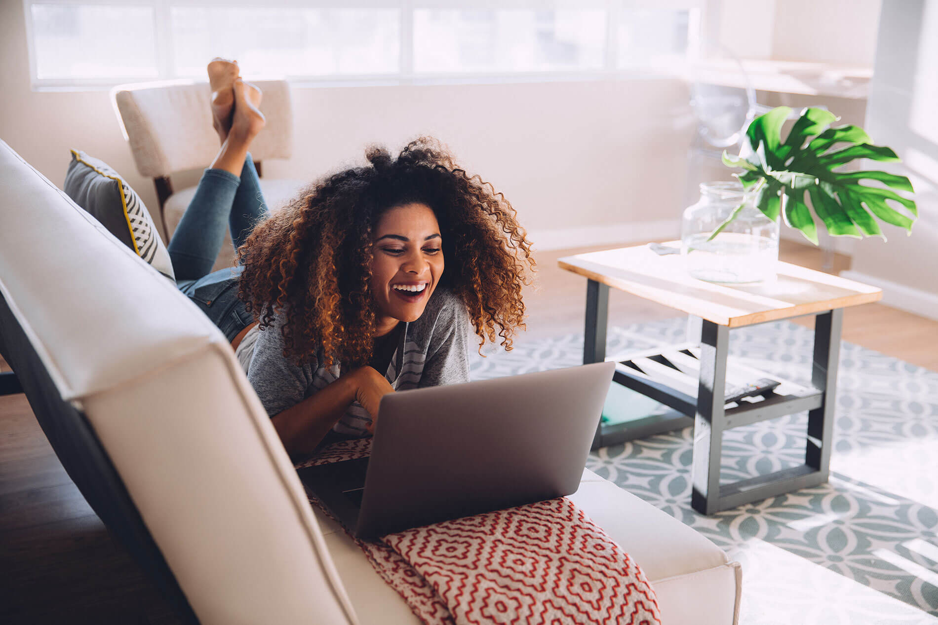 Woman smiling on couch with laptop