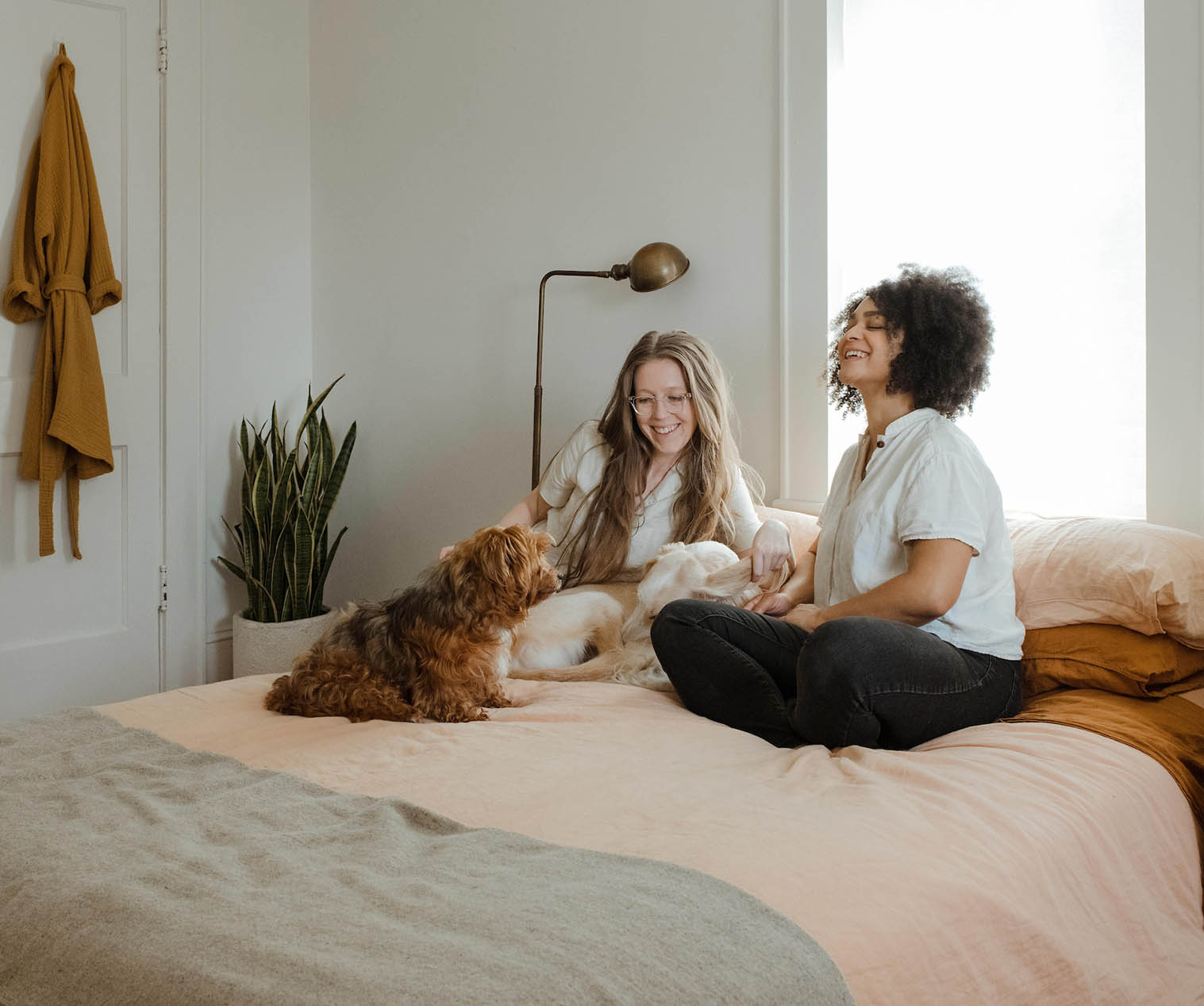 Female friends and dog sitting together on bed