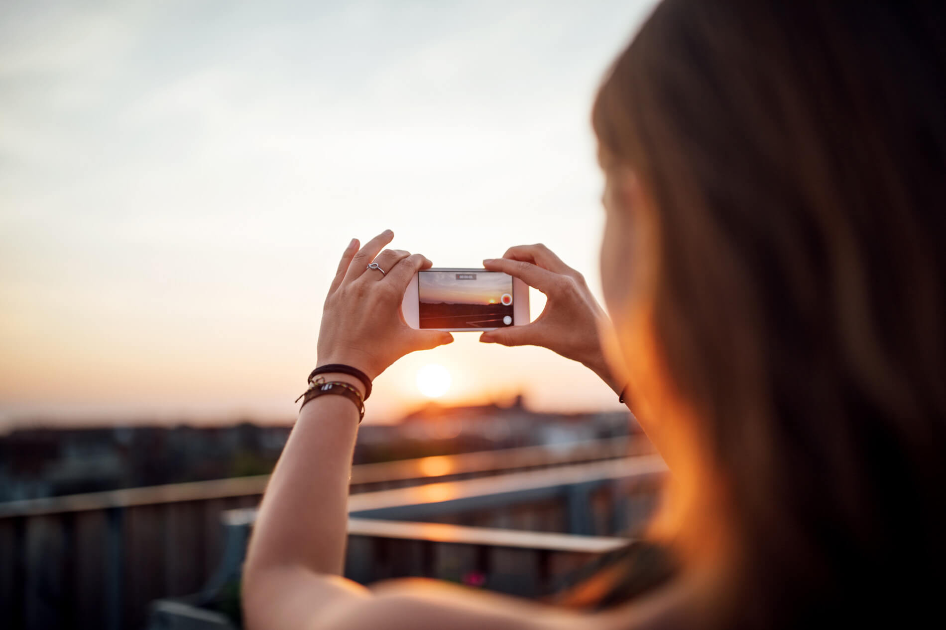 Woman taking photo of sunset