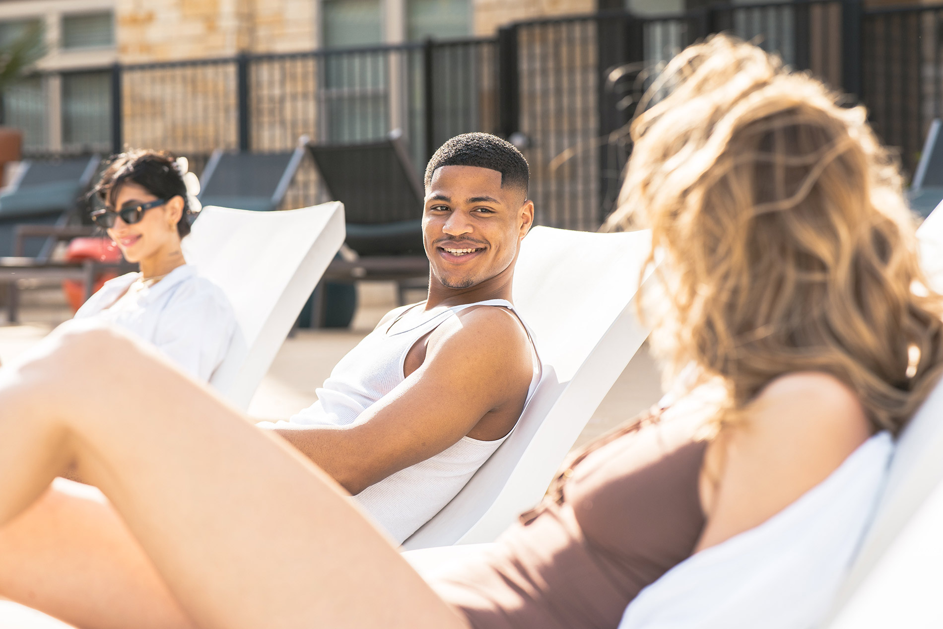 Vitruvian West three people lounge by the pool