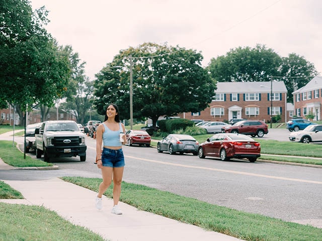 A woman walks on the sidewalk beside Rodgers Forge
