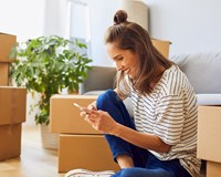 woman on phone surrounded by moving boxes