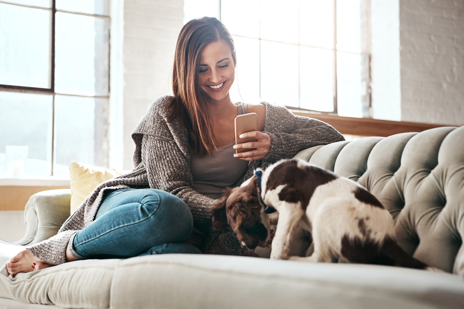 a woman sitting on a couch looking at her cell phone