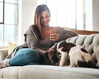 a woman sitting on a couch looking at her cell phone