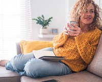 a woman sitting on a couch holding a cup of coffee