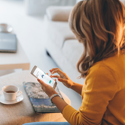 woman on phone setting smart thermostat